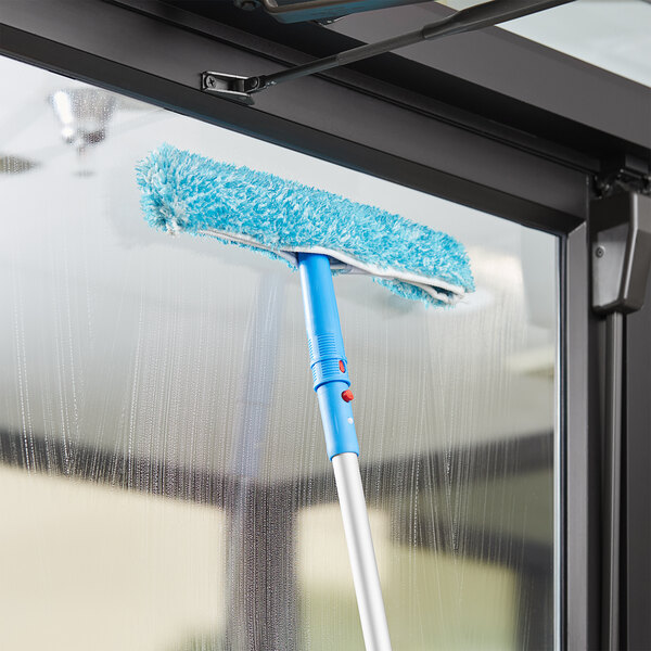 A blue Lavex mop with a handle cleaning a window.