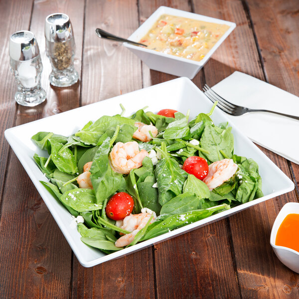 A white bowl with a salad of shrimp and tomatoes in it.
