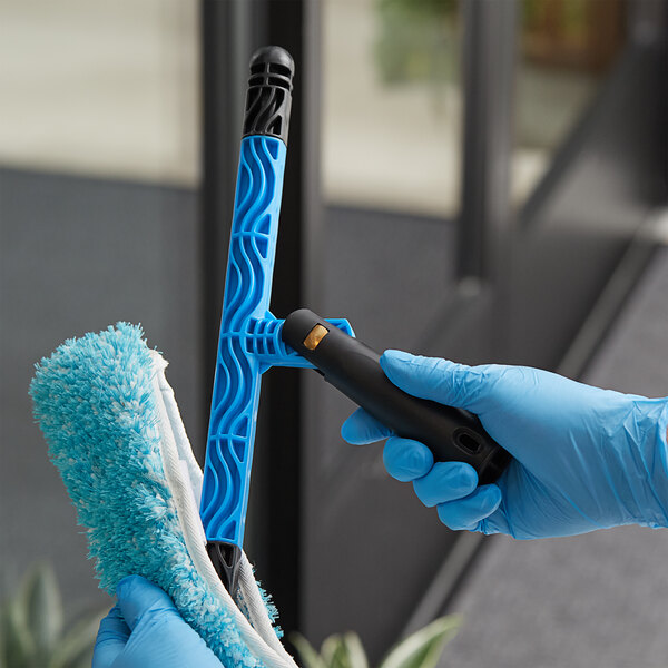 A person in blue gloves holding a black Lavex swivel T-bar handle.