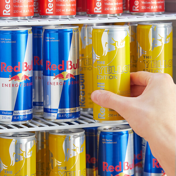 A person holding a yellow Red Bull can.