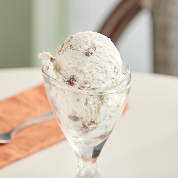 A glass bowl with a scoop of SNICKERS® chocolate topping on ice cream.