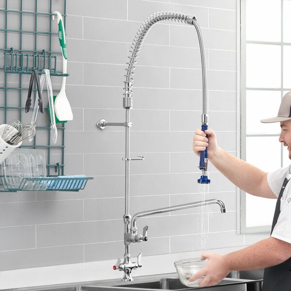 A man using a Waterloo pre-rinse faucet to pour water into a bowl on a counter in a professional kitchen.
