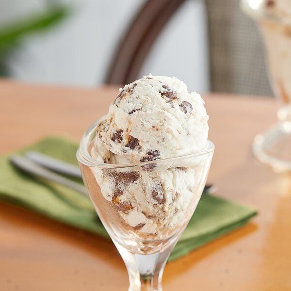A glass bowl with a scoop of Gertrude Hawk Mini Milk Chocolate Caramel Turtle on top of ice cream.