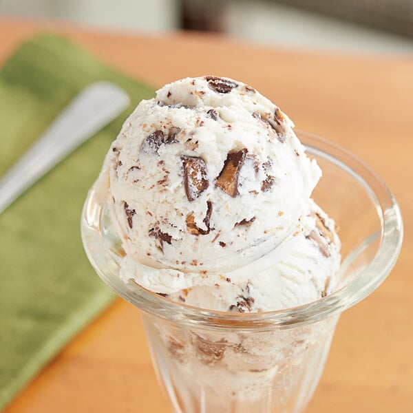 A scoop of ice cream with a Mini Milk Chocolate Peanut Butter Cup in a glass cup.