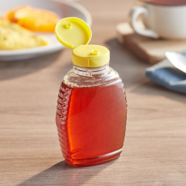 A Classic Queenline PET honey bottle with a yellow cap and heat induction seal liner filled with honey.