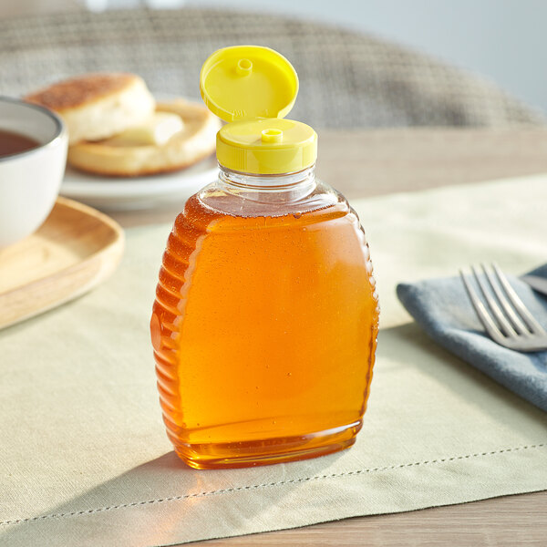 A Classic Queenline PET honey bottle with yellow cap on a table.