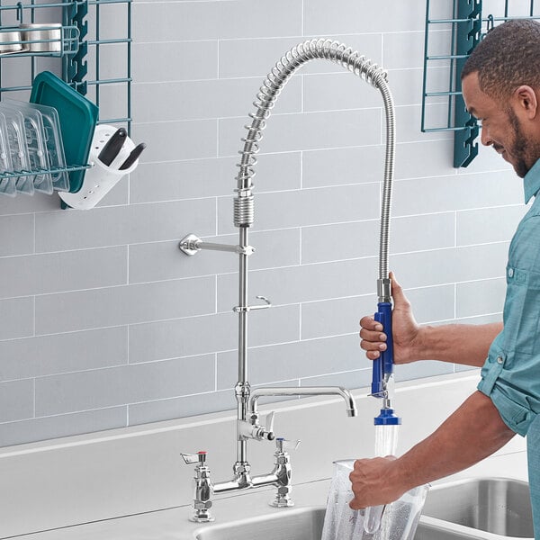 A man using a Waterloo pre-rinse spray valve to wash his hands in a professional kitchen sink.
