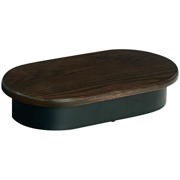 A brown oak display riser on a wooden table with a black base.
