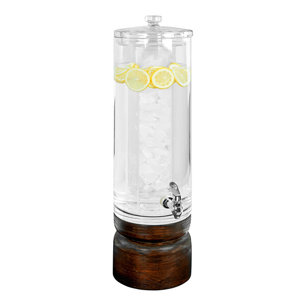 A Cal-Mil plastic beverage dispenser with ice and lemons inside on a dark wood base.
