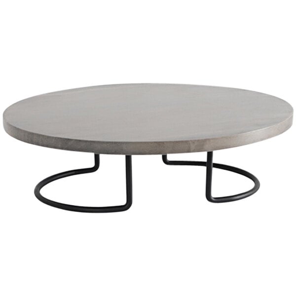 A round concrete table with a Cal-Mil black and gray pine display riser on top.
