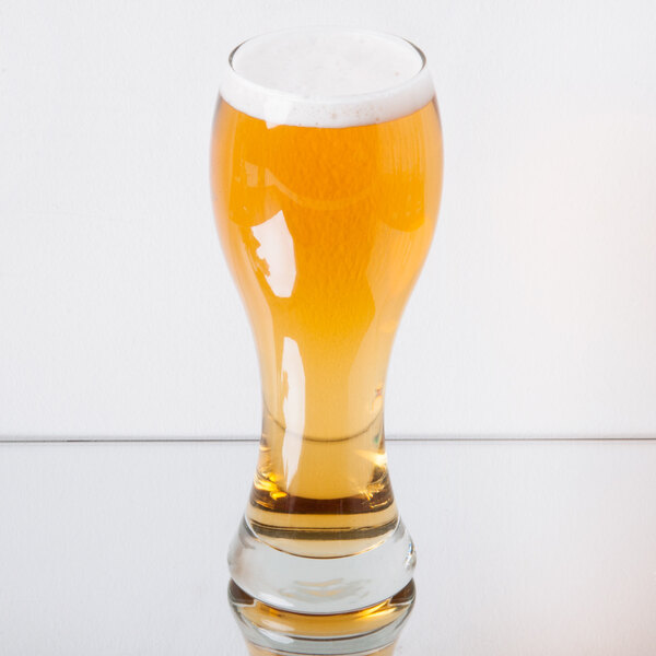 A Libbey Giant Pilsner Glass filled with beer on a table.