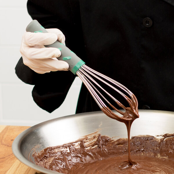 A person using a Vollrath stainless steel French whip to mix chocolate batter.