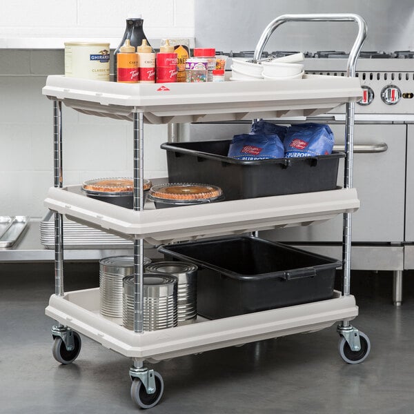 A gray Metro utility cart with three deep ledge shelves holding food items.