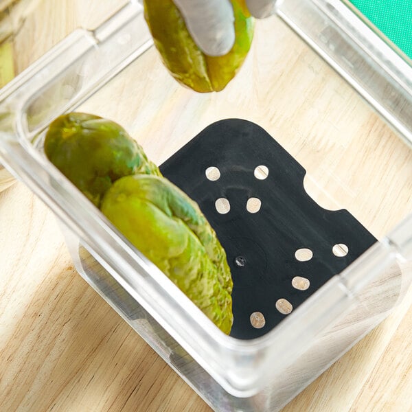 A hand using a Cambro black polycarbonate drain tray to hold pickles.