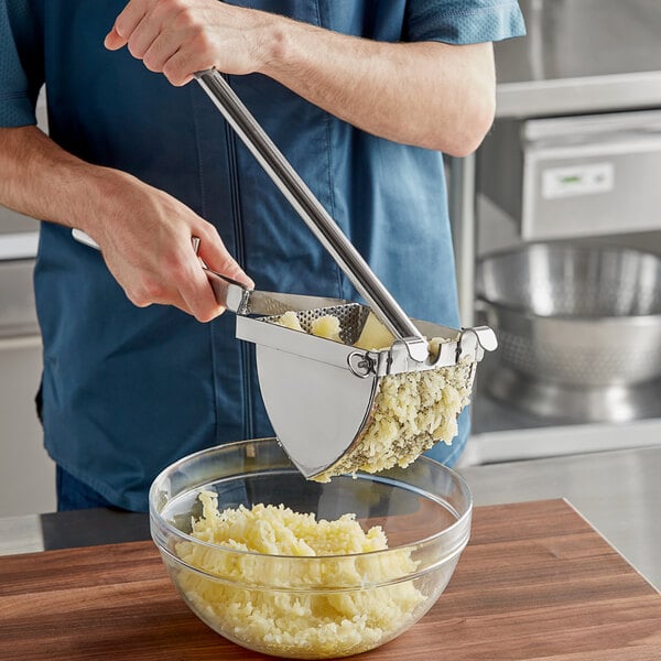 A person using a Choice stainless steel potato ricer to press potatoes into a bowl.