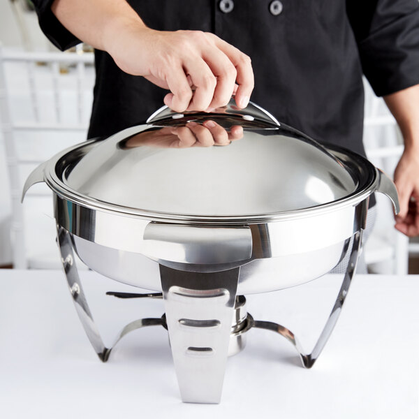 A person holding a silver Vollrath Maximillian chafing dish lid.