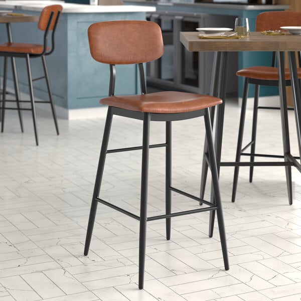 A Lancaster Table & Seating mid-century black barstool with a brown vinyl seat and backrest.