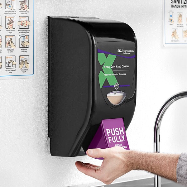 A SC Johnson Professional Solopol hand soap dispenser on a wall above a purple box with white text.
