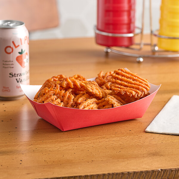 A red paper food tray of nacho fries and a can of soda on a table.