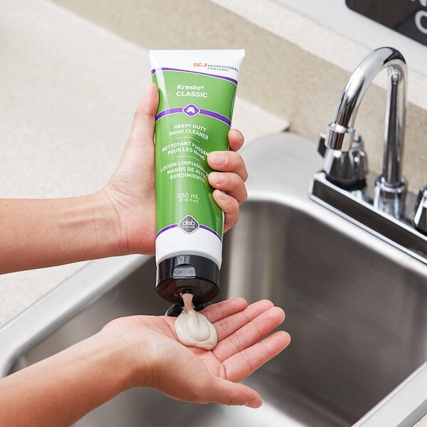 A hand holding a green SC Johnson Professional Kresto Classic lotion bottle pouring onto a hand