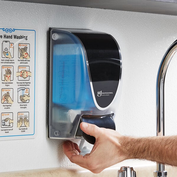 A person using a SC Johnson Professional QuickView 1 liter soap dispenser to wash their hands.