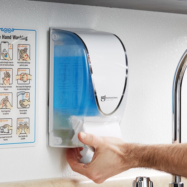 A person using a SC Johnson soap dispenser on a counter.