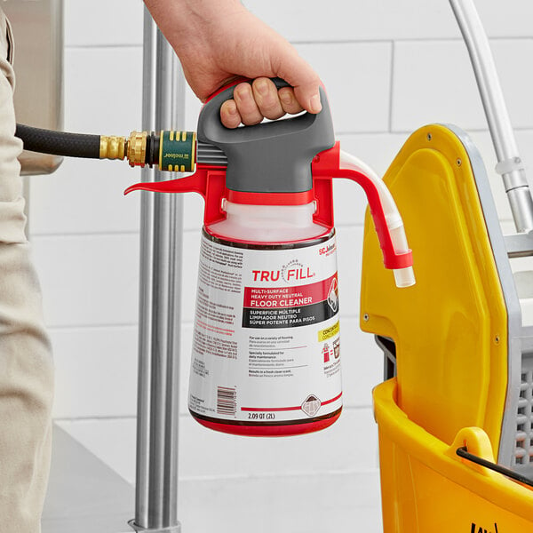A person holding a yellow SC Johnson Professional TruFill sprayer over a yellow bucket.