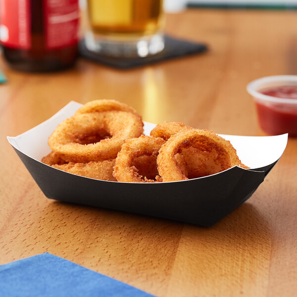 A black paper food tray holding fried onion rings.
