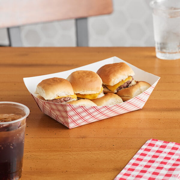 A red plaid paper food tray with hamburgers on a table.
