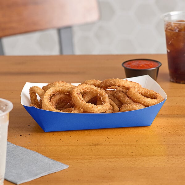 A blue paper food tray of fried onion rings on a table.