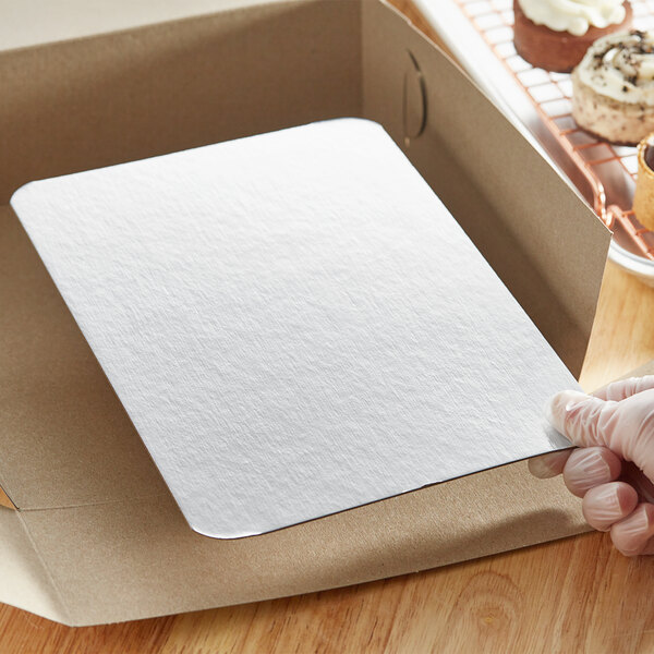 A hand holding a white rectangular Enjay dessert board in a box.