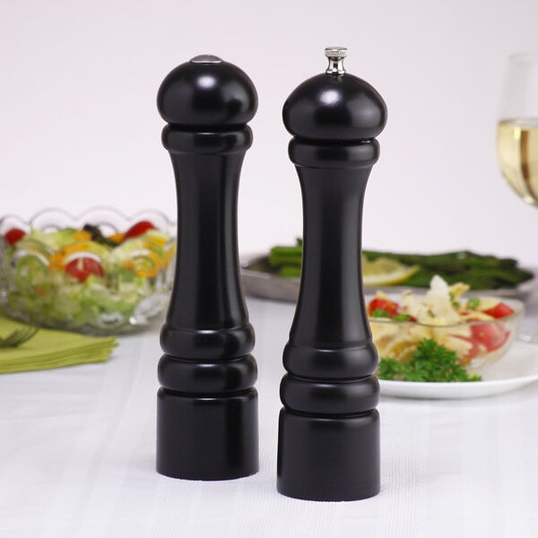 A black Chef Specialties pepper mill and salt shaker set on a table.