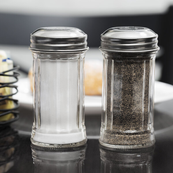 Two Tablecraft fluted glass salt and pepper shakers with stainless steel tops on a table.