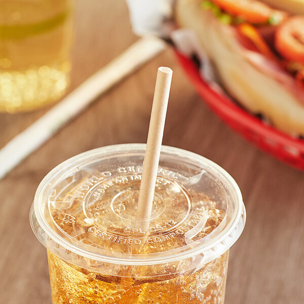 A plastic cup with a World Centric paper straw in it on a table.