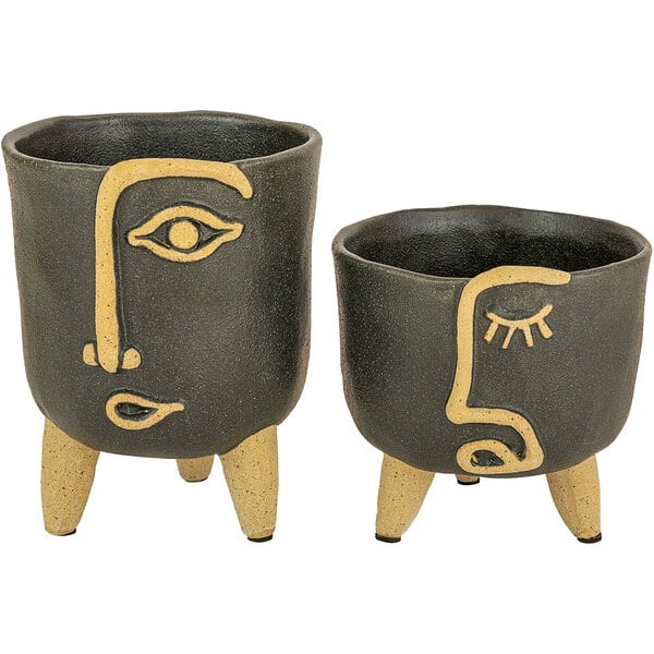 A pair of black and yellow Kalalou ceramic pots with faces on them.