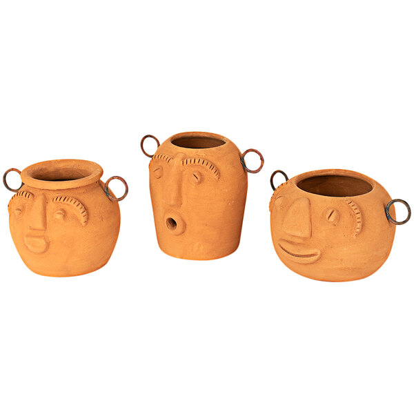 A group of three clay pots with faces on them.