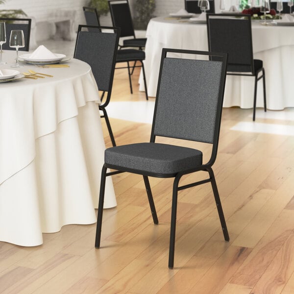 A Lancaster Table & Seating banquet chair with gray fabric and black frame next to a table in a restaurant.