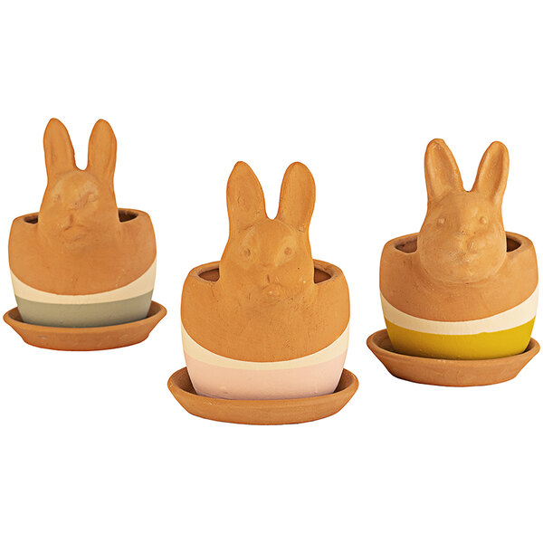 A group of three clay bunny shaped pots with faces on them.
