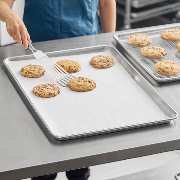 A woman using a Full Size Light Weight Silicone Coated Parchment Paper Sheet to bake cookies on a sheet pan.