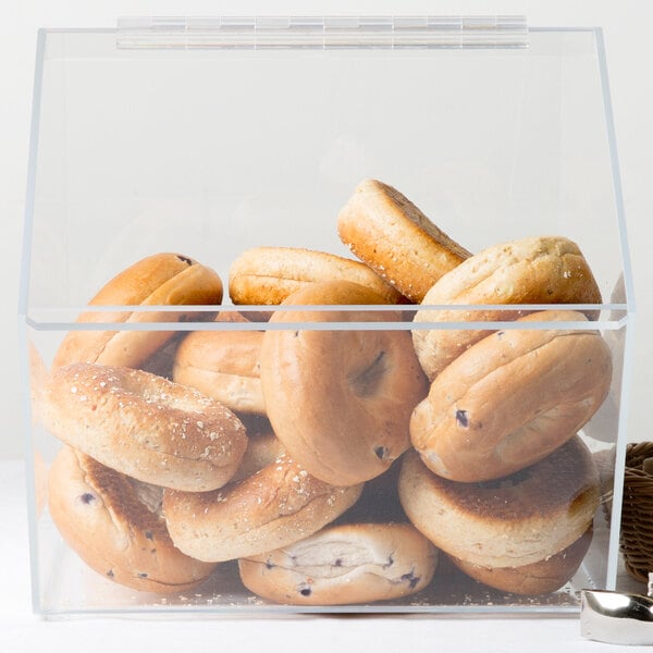 A clear plastic Cal-Mil food bin filled with bagels.