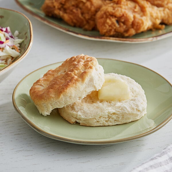 A Pillsbury Golden Buttermilk biscuit on a plate next to a bowl of food.