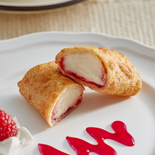 A white plate with two El Monterey Raspberry Cheesecake Chimis topped with raspberry sauce.