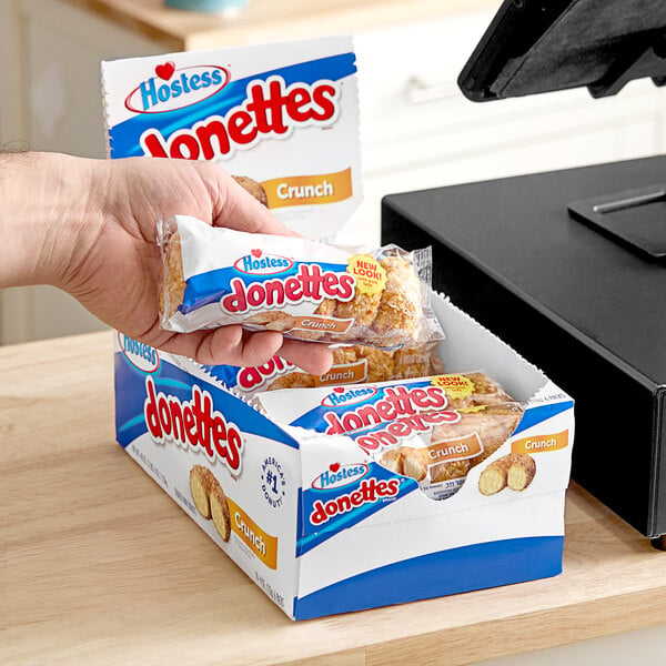 A hand holding a box of Hostess Donettes with Coconut Topping.