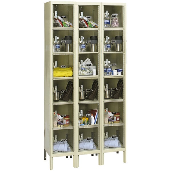 A tan metal Hallowell Safety-View triple box locker with many shelves and containers inside.