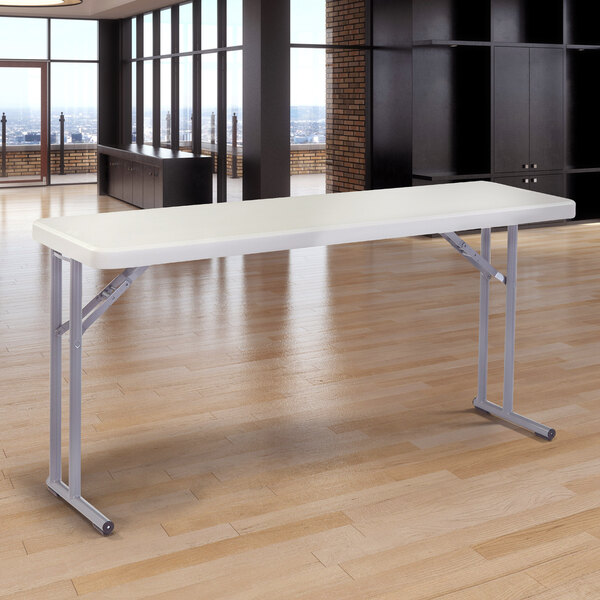 A National Public Seating speckled gray plastic folding seminar table on a wood floor.
