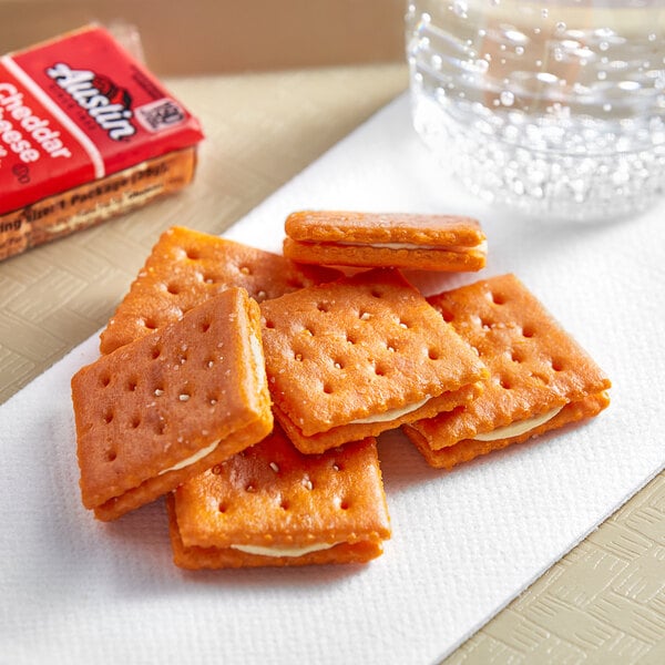 Austin Cheddar Cheese on Cheese Sandwich Crackers package on a table with a group of crackers and a glass of water.