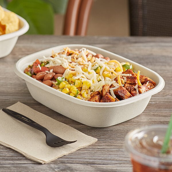 A white World Centric compostable fiber box filled with food on a table.