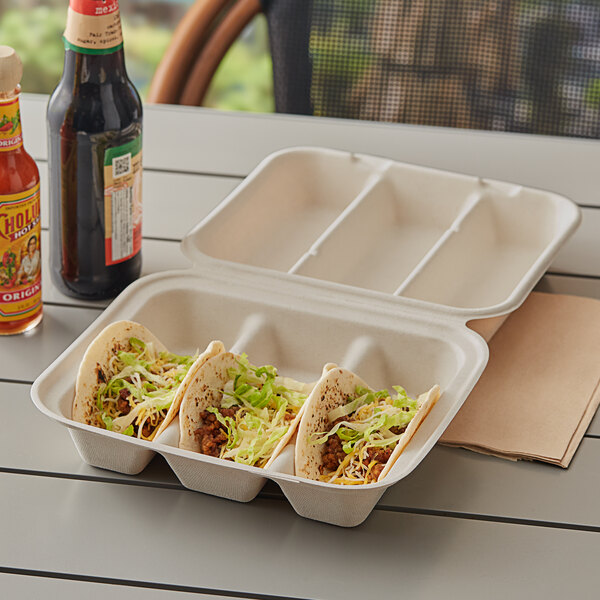 A white World Centric 3-compartment container of tacos with meat and lettuce on a table.
