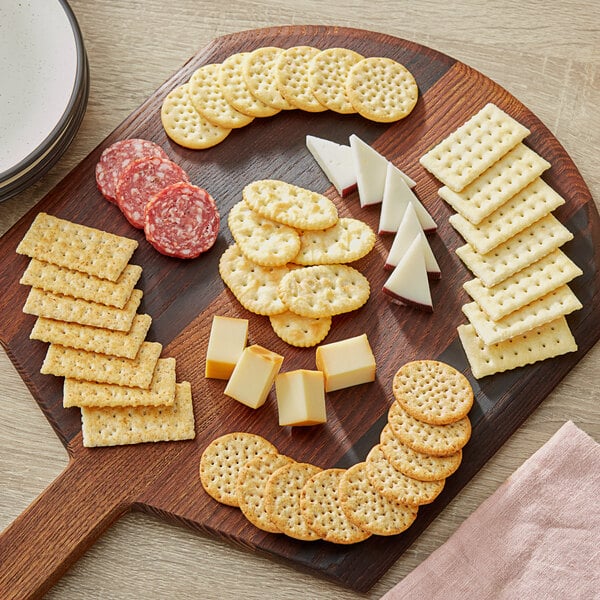 A wooden cutting board with Kellogg's Cracker Medley, cheese, and other snacks.