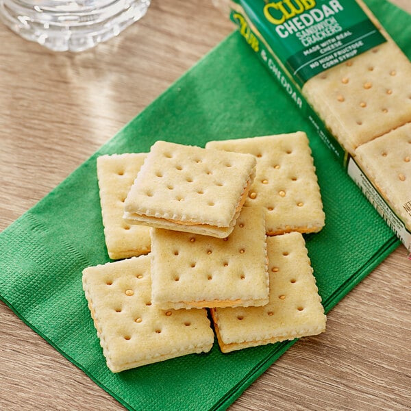 A close up of a box of Keebler Club and Cheddar Sandwich Crackers on a green napkin.